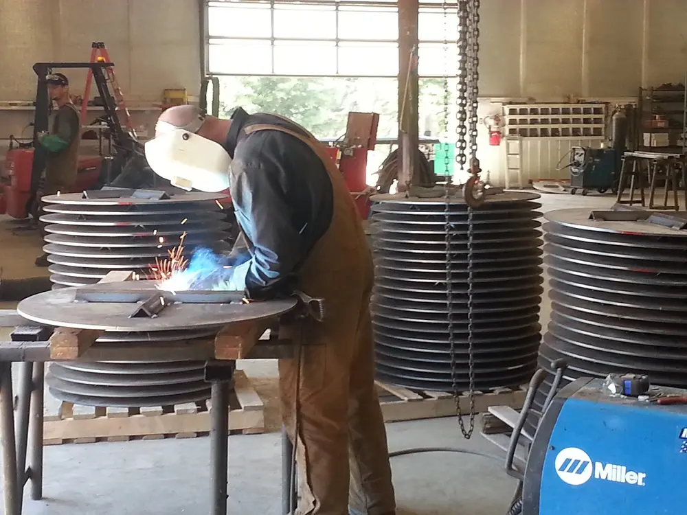 A man welding metal in an industrial setting.